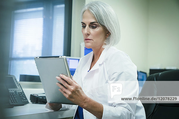 Serious Caucasian doctor using digital tablet