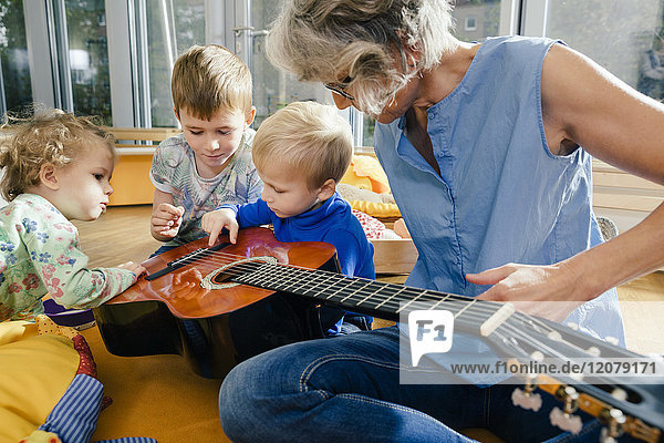 Vorschullehrer zeigt Kindern im Kindergarten eine Gitarre