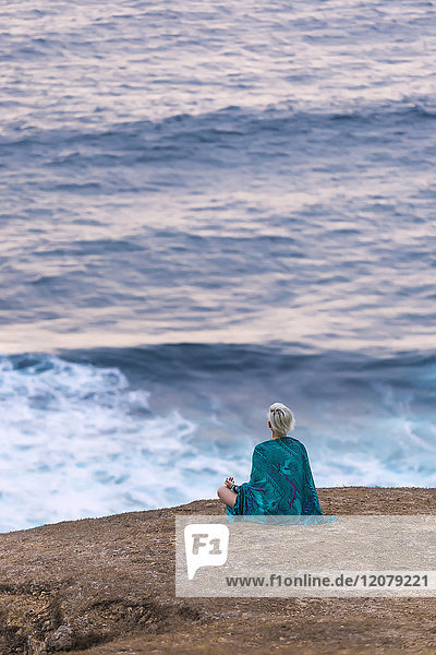 Indonesien  Lombok  Frau an der Küste sitzend mit Blick auf die Küste