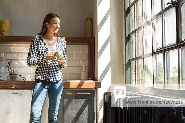 Junge Unternehmerin in der Firmenküche stehend  Kaffee trinkend