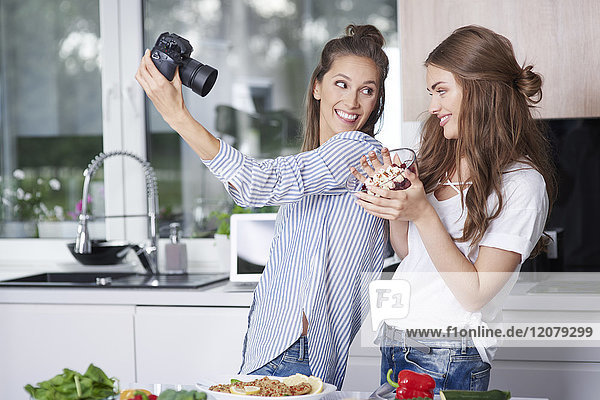 Food bloggers taking selfie with digital camera