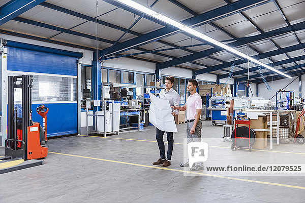 Two businessman standing in shop floor  discussing plans