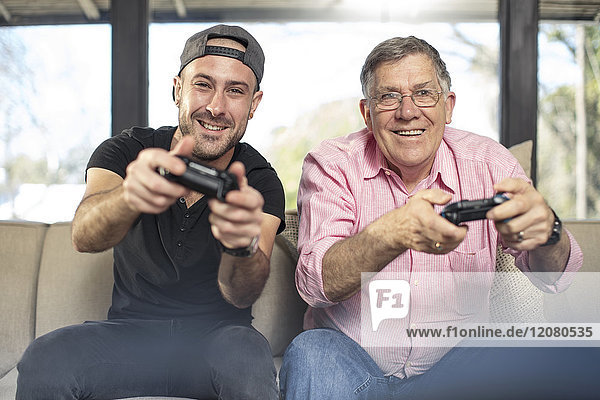 Happy grandfather and grandson playing video game on couch at home