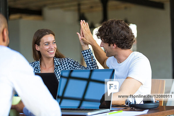 Young cooleagues working together in start up company  giving high five
