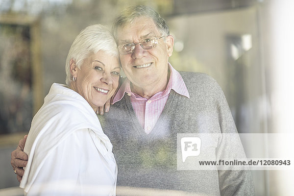 Portrait of smiling senior couple behind windowpane