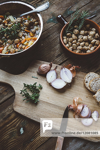 Mediterrane Suppe im Kupferkessel,  Schüssel mit Croutons und Zutaten auf Holzbrettchen
