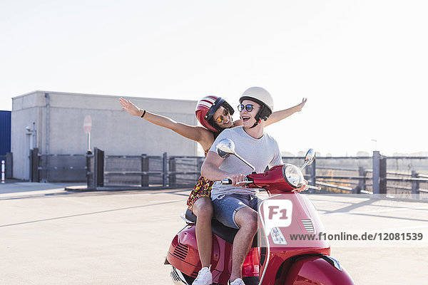 Sorgenfreies junges Paar auf dem Motorroller auf der Parkebene