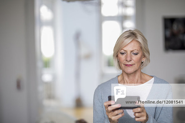 Portrait of senior woman at home looking at cell phone