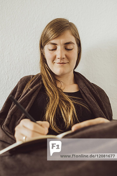 Smiling woman writing in notebook at home