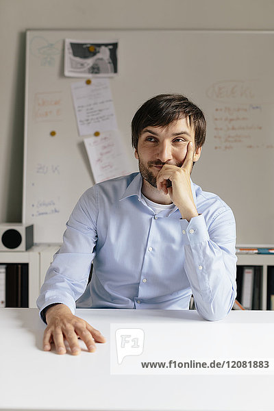 Porträt eines lächelnden Geschäftsmannes am Schreibtisch im Büro