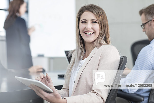 Porträt einer lachenden Geschäftsfrau mit Tablette auf einem Meeting im Konferenzraum