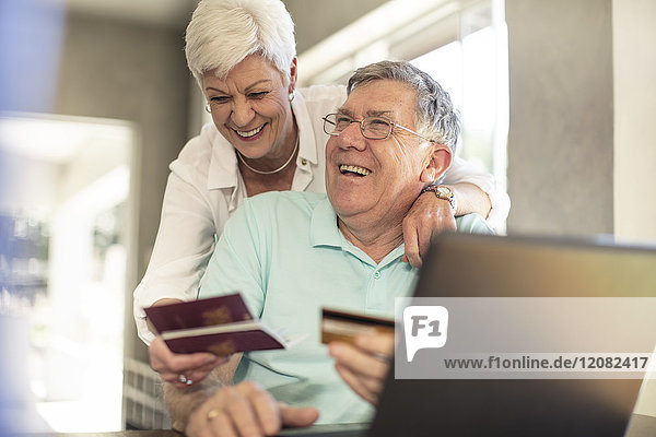 Glückliche Seniorenpaare mit Reisepässen  die ihre Reise gemeinsam online buchen.