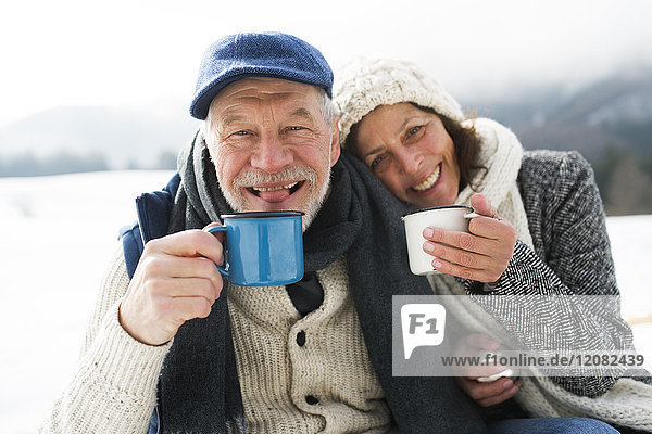 Porträt eines Seniorenpaares mit heißen Getränken im Winter