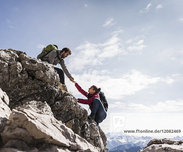 Deutschland  Bayern  Oberstdorf  Mann hilft Frau beim Klettern auf den Felsen