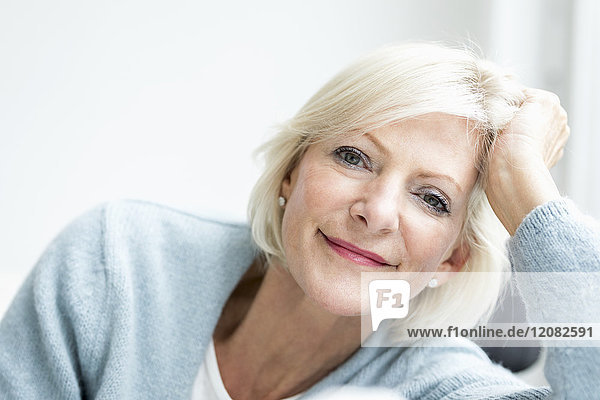 Porträt einer lächelnden Seniorin mit Kopf in der Hand