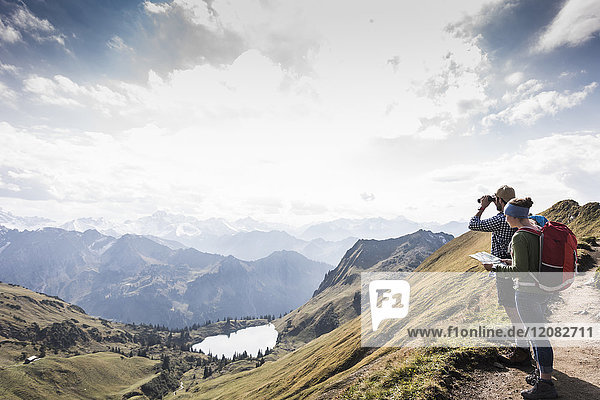 Deutschland  Bayern  Oberstdorf  zwei Wanderer mit Karte und Fernglas in alpiner Landschaft