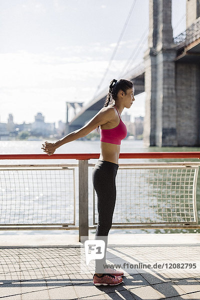 Woman doing stretching exercises in Manhattan near Brooklyn Bridge in the morning