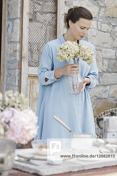 Italien  Frau mit Blumenköpfen von Hortensia in Vase auf Terrasse