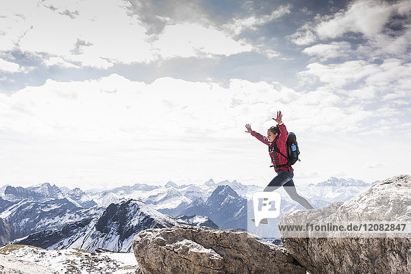 Deutschland  Bayern  Oberstdorf  Frau springt auf Felsen in alpiner Landschaft