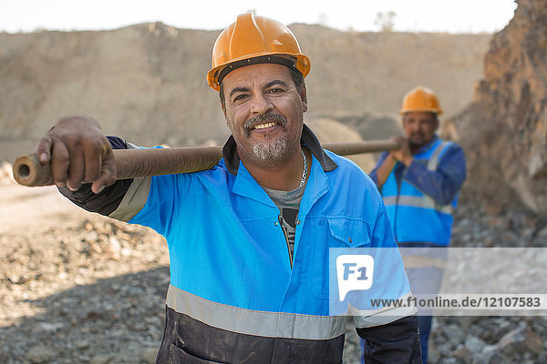 Porträt von Steinbrucharbeitern im Steinbruch  die ein Metallrohr tragen