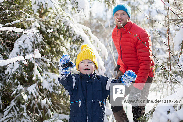 Man and son pointing while walking through snow covered forest