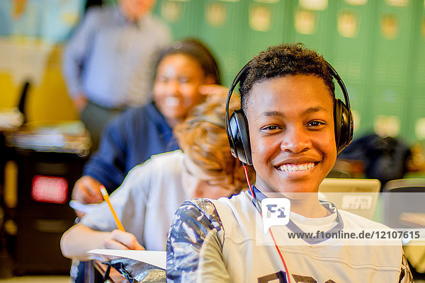 Porträt eines Teenager-Schülers mit Kopfhörern am Klassenpult