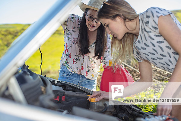 Zwei junge Frauen  neben dem Auto  Blick auf den Motor