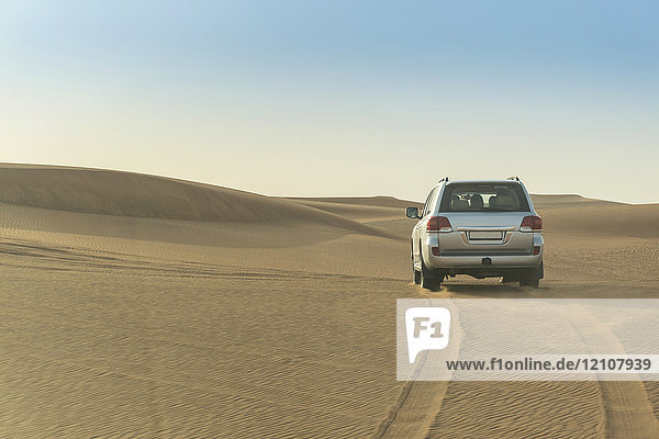 Geländefahrzeug fährt über Wüstendünen  Dubai  Vereinigte Arabische Emirate