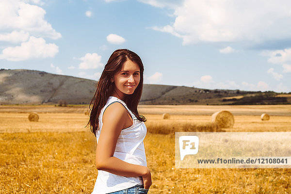 Porträt einer Frau im Weizenfeld  die lächelnd in die Kamera schaut
