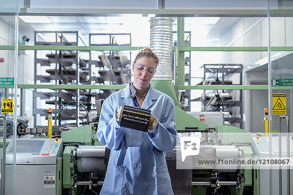 Weibliche Bedienungsperson mit Kohlenstofffaserspule in einer Kohlenstofffaser-Produktionsanlage