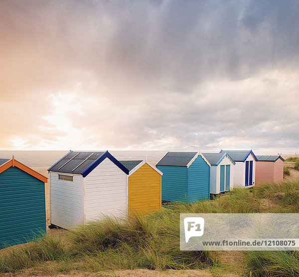 Reihe von bunten Strandhütten und Sturmwolken über dem Meer  Southwold  Suffolk  England