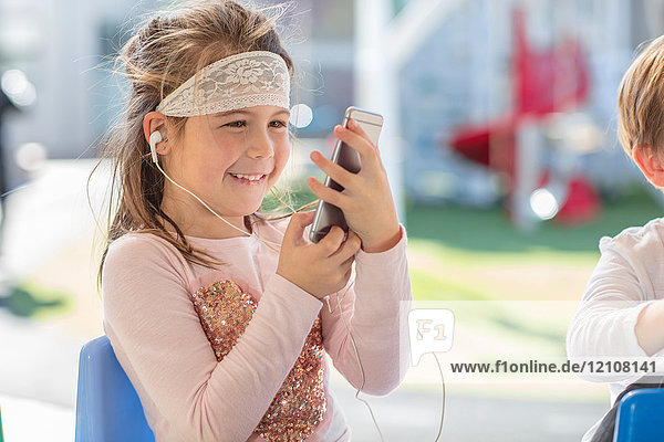 Junges Mädchen mit Smartphone  das Kopfhörer trägt
