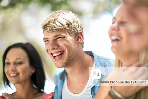 Vier junge und mittel-erwachsene Freunde lachen bei Strandparty