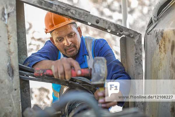 Steinbrucharbeiter im Steinbruch  der sich um die Maschinen kümmert
