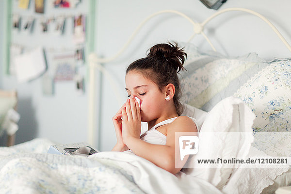 Girl in bed blowing nose on handkerchief