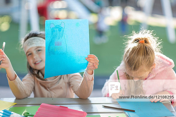 Zwei junge Mädchen  im Freien  Zeichnung  junges Mädchen hält Kunstwerk hoch