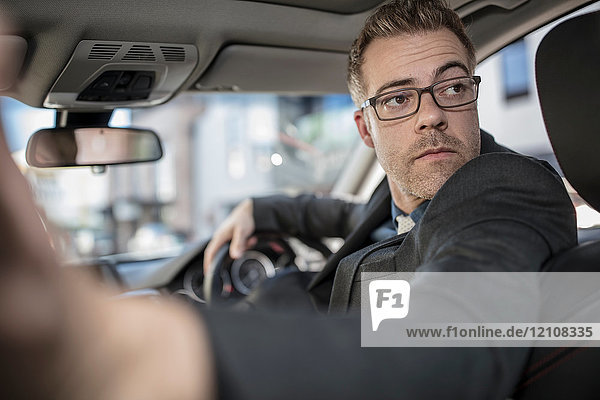 Businessman driving car  looking over shoulder  reversing