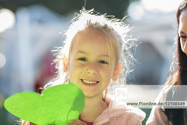 Junges Mädchen im Freien  grünes Papierherz haltend  lächelnd