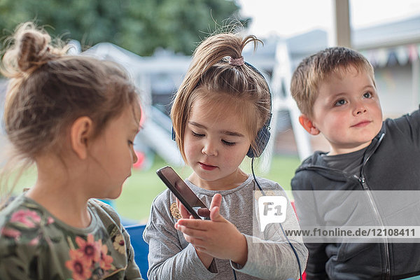 Junges Mädchen mit Freunden  mit Smartphone  mit Kopfhörern