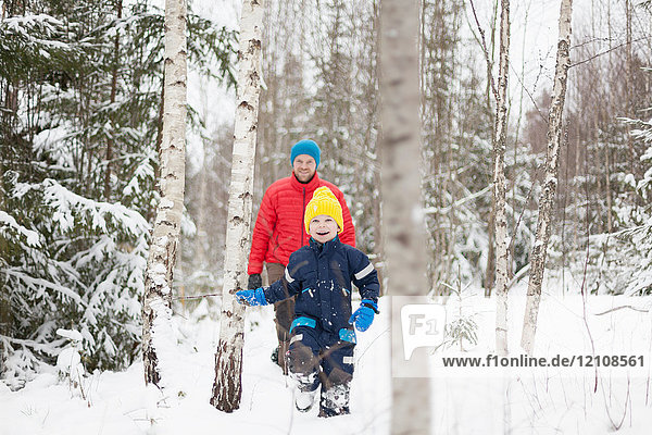 Mann und Sohn gehen im verschneiten Wald spazieren