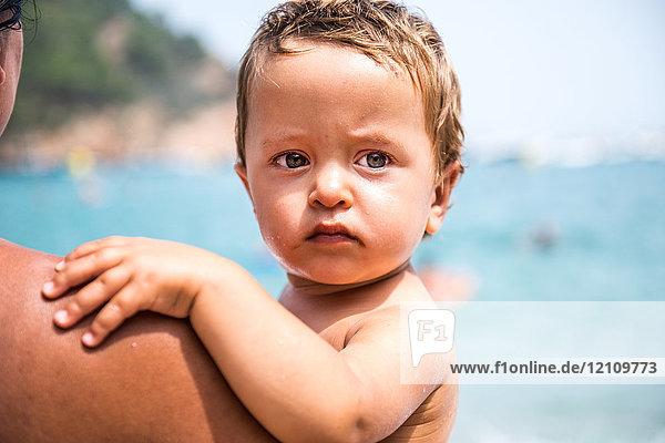 Über-Schulter-Ansicht einer Mutter  die einen männlichen Kleinkind-Sohn am Strand trägt  Begur  Katalonien  Spanien
