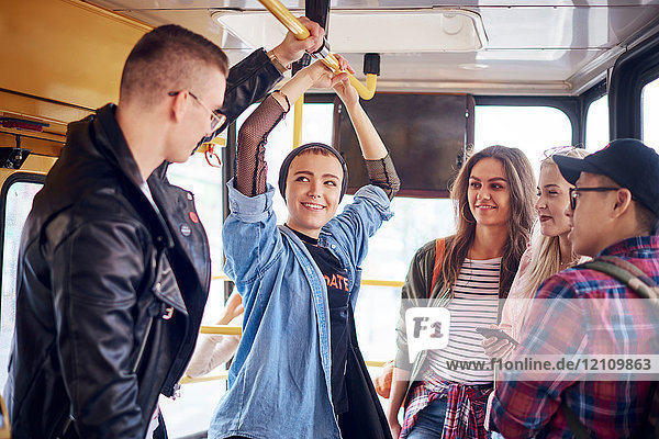 Five young adult friends chatting on city tram