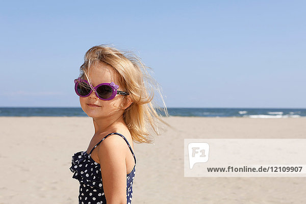 Portrait of girl on beach wearing swimming costume and sunglasses