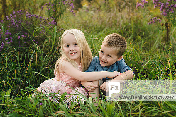 Junge und Mädchen sitzen zusammen im hohen Gras