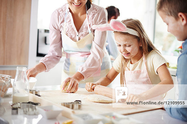 Mädchen mit Mutter und Bruder backt zu Ostern an der Küchentheke
