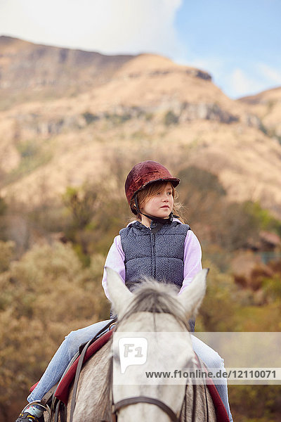 Mädchen reitet Pferd in ländlicher Umgebung