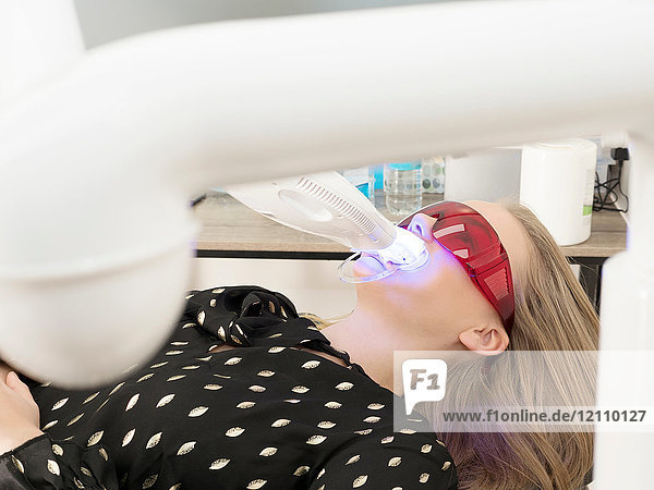 Junge Frau auf Zahnarztstuhl  die ihre Zähne bleichen lässt
