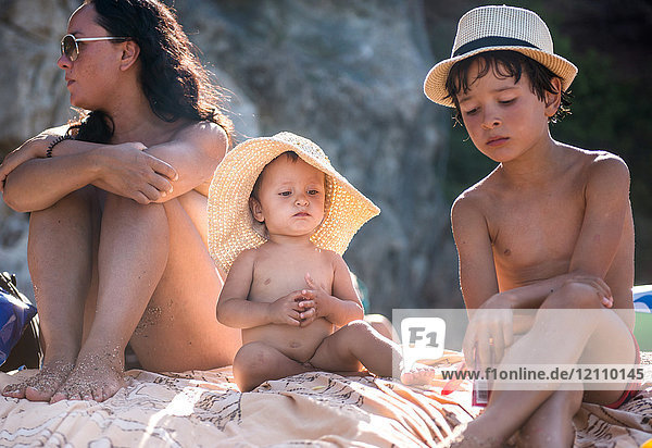 Frau und zwei Söhne sitzen am Strand  Begur  Katalonien  Spanien
