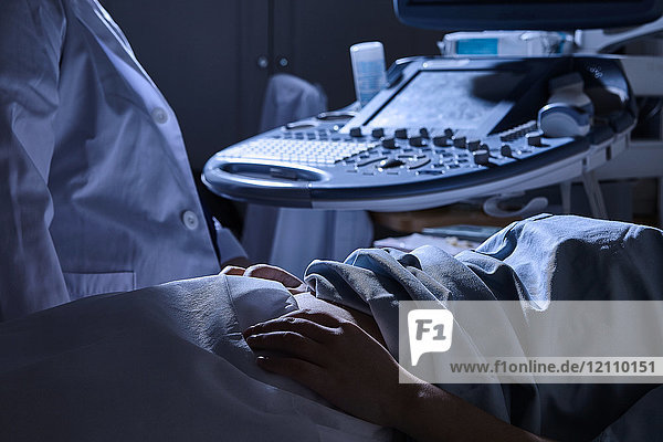 Schrägansicht der Ultraschalluntersuchung einer schwangeren Patientin durch den Sonographen