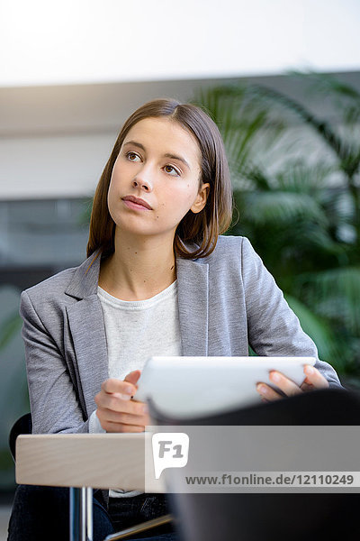 Junge Geschäftsfrau mit Laptop in Besinnung am Büroschreibtisch